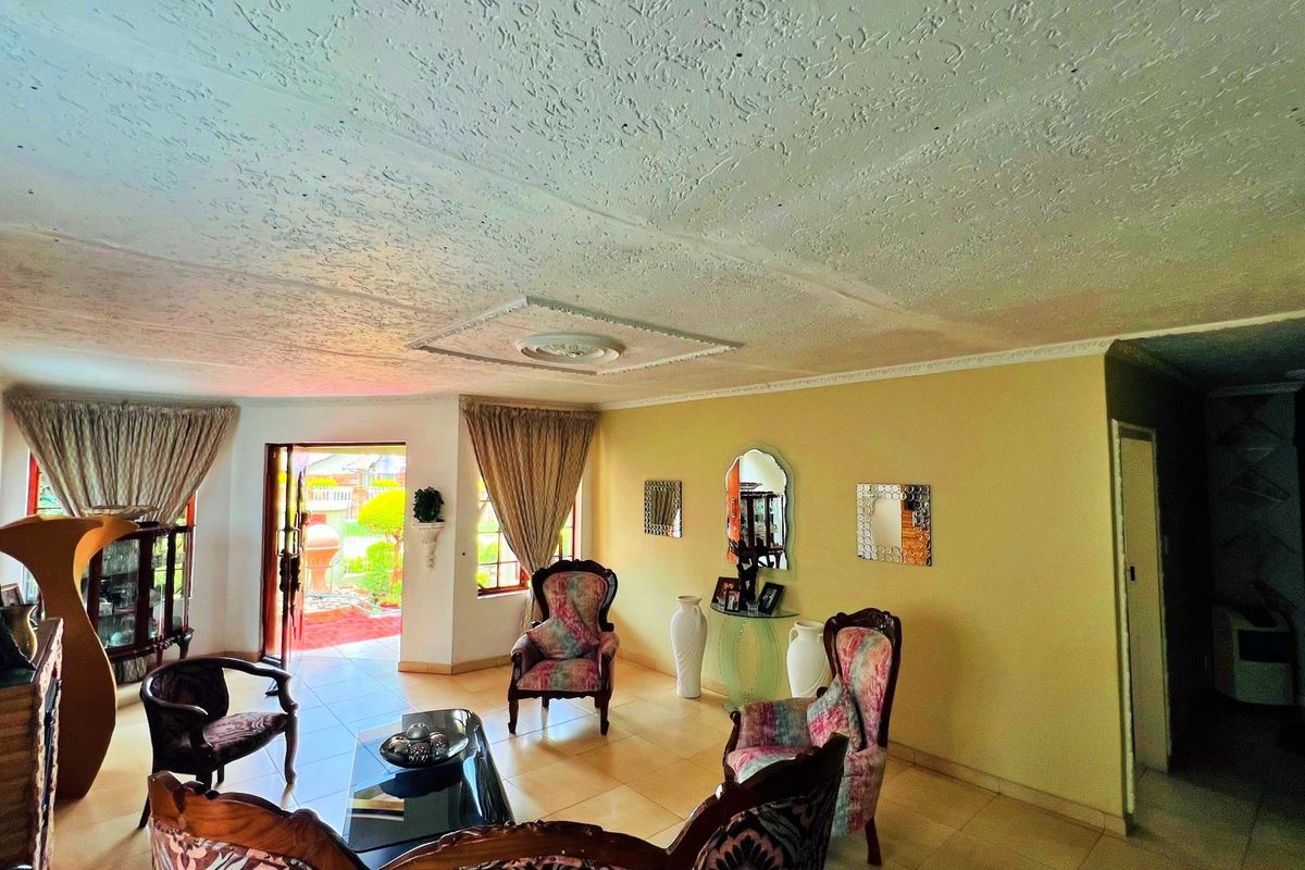 A spacious living room featuring tiled flooring, textured ceilings with decorative cornicing, and direct access to an outdoor patio area.