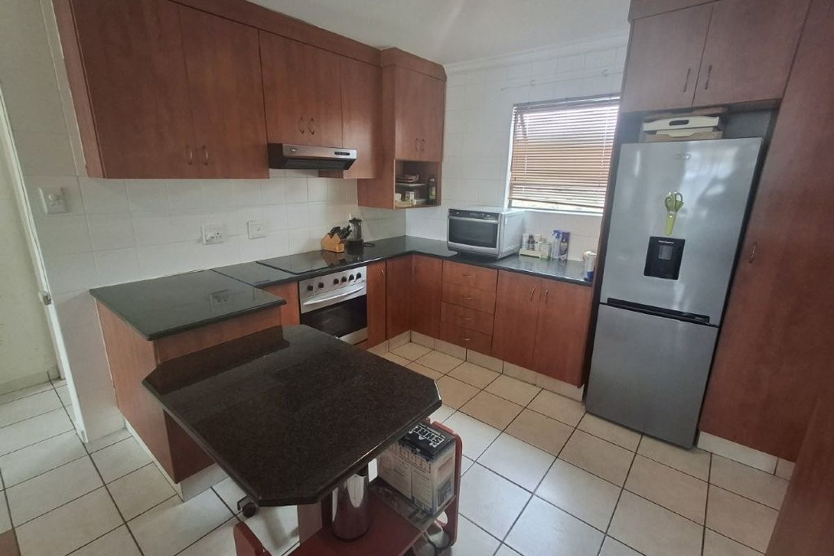 A functional kitchen featuring dark wood cabinetry, granite countertops, tiled flooring, and a built-in stove with an extractor fan.