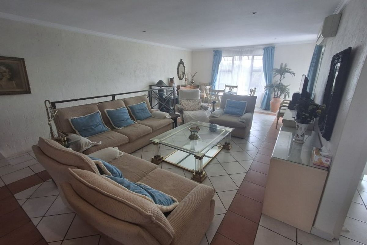 Spacious living room featuring tiled flooring, recessed lighting, and a wall-mounted air conditioning unit with access to a bright window area.