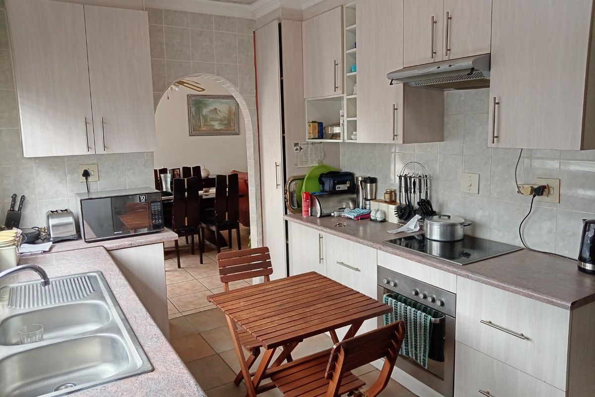 Functional kitchen featuring laminate cabinetry, built-in oven, electric cooktop, and tiled backsplash, with an open archway leading to the dining area.