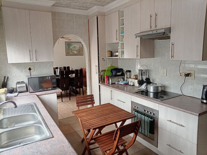Functional kitchen featuring laminate cabinetry, built-in oven, electric cooktop, and tiled backsplash, with an open archway leading to the dining area.