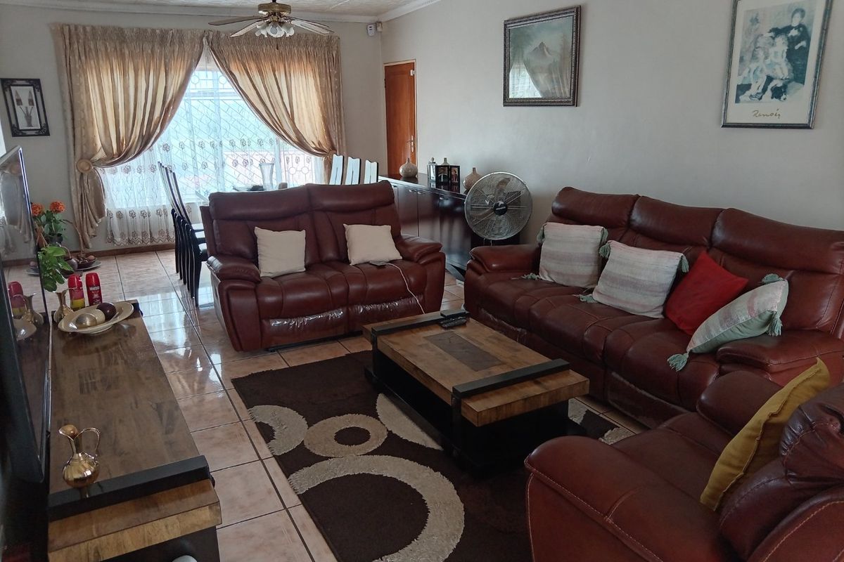 Spacious living room featuring tiled flooring and decorative ceiling tiles, offering a comfortable and functional layout for family relaxation.