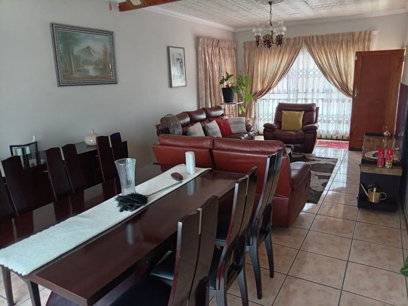 Spacious open-plan living and dining area featuring tiled flooring, a decorative ceiling, and large sliding doors providing access to the exterior.