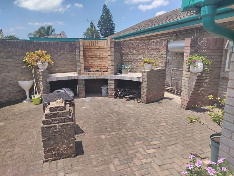 Outdoor patio area featuring a built-in brick braai and paved flooring, enclosed by a brick boundary wall.