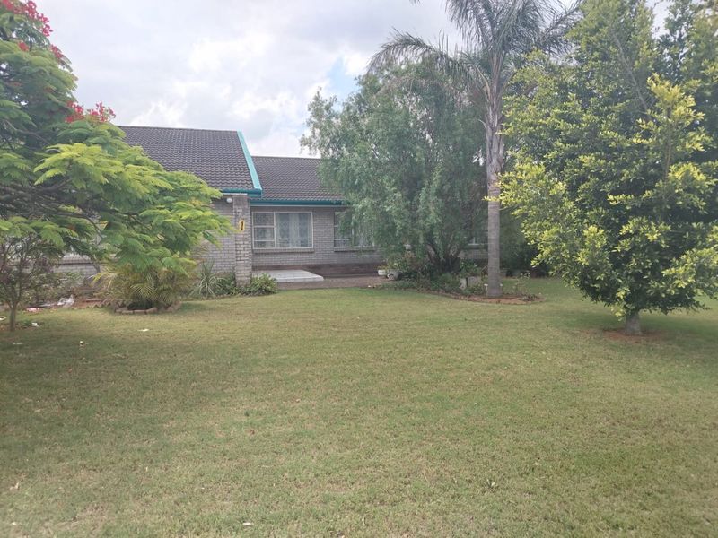 Front view of a single-story brick house featuring a tiled roof, paved entrance path, and a well-maintained front garden.