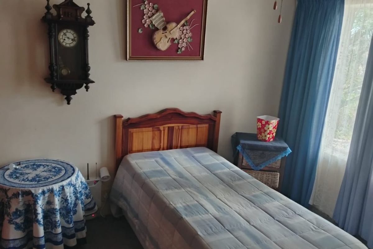 A functional bedroom featuring a ceiling fan and window with curtain tracks, providing a neutral space ready for modernization.