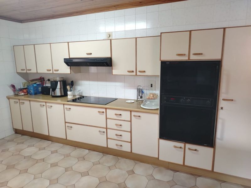 A functional kitchen featuring built-in cabinetry, a double oven, electric hob, and tiled backsplash, offering a classic layout ready for modern updates.
