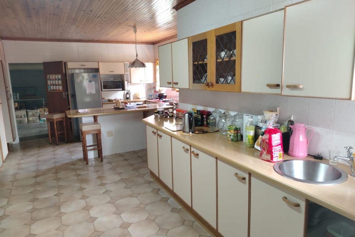 A spacious kitchen featuring timber ceilings, laminate countertops, a breakfast bar, and ample built-in cabinetry, offering a functional layout with potential for modern updates.