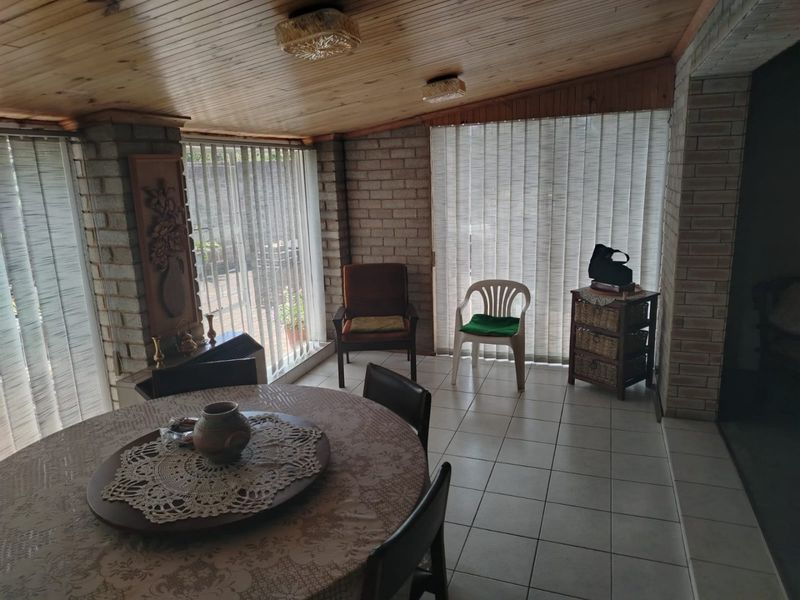 A covered patio area featuring exposed brick walls, a timber-clad ceiling, and ceramic floor tiles, providing a versatile space for indoor-outdoor living.