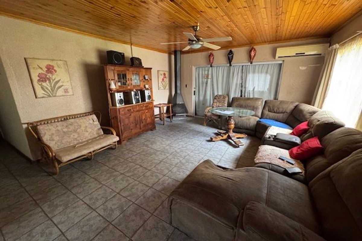 Spacious living room featuring a timber-clad ceiling, tiled flooring, a freestanding fireplace, and a split-system air conditioner with access to the outdoor area.