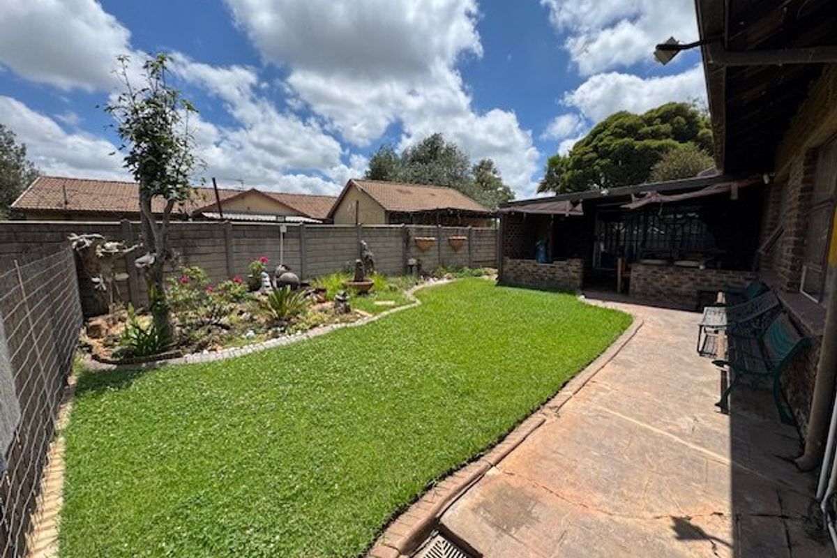 A well-maintained rear garden featuring a paved patio area, lawn, and brick boundary walls, providing a private outdoor space.