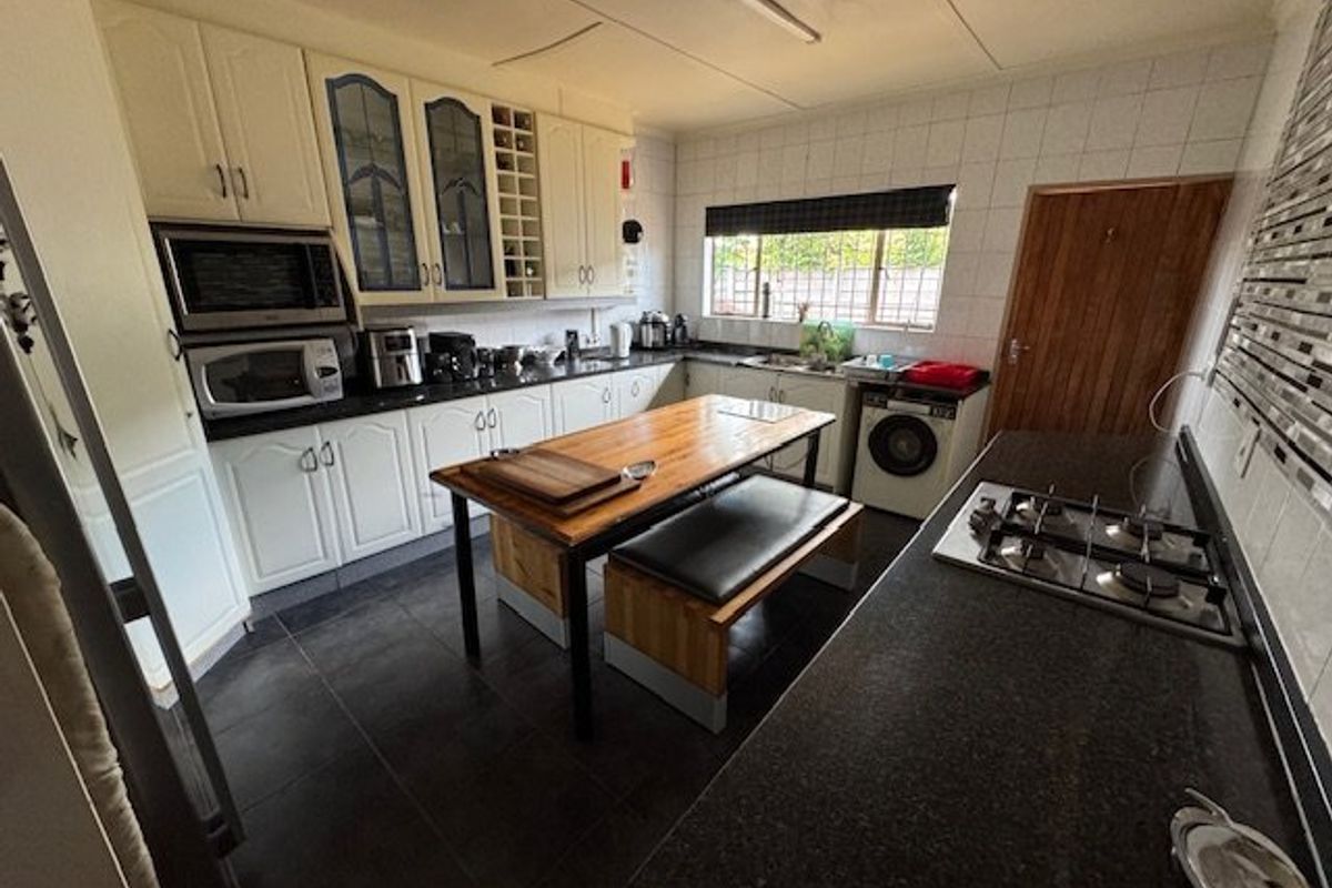 Functional kitchen featuring granite countertops, built-in oven and microwave, gas hob, and integrated laundry space with ample cabinetry storage.