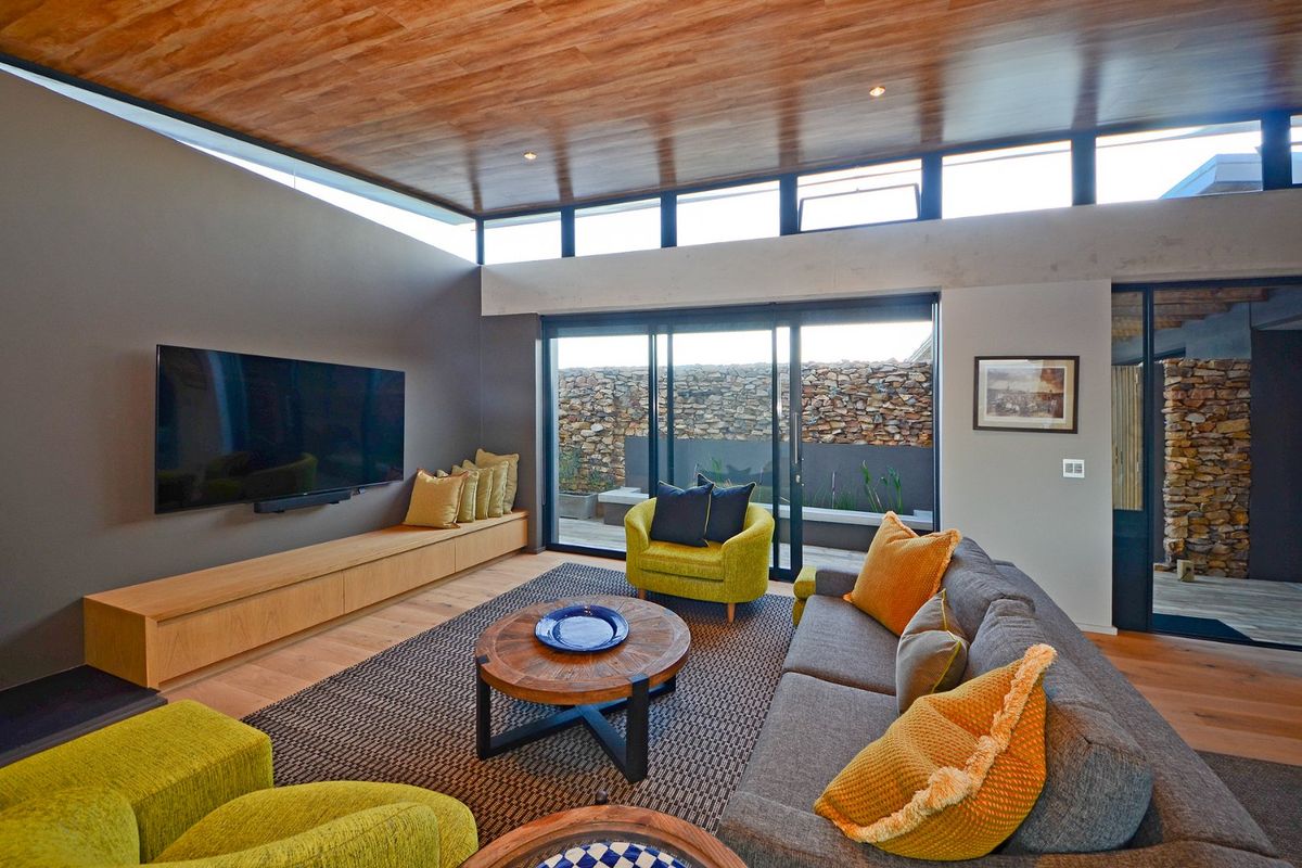 Modern living room featuring a warm timber ceiling, clerestory windows for natural light, and large sliding glass doors opening to an outdoor patio area.