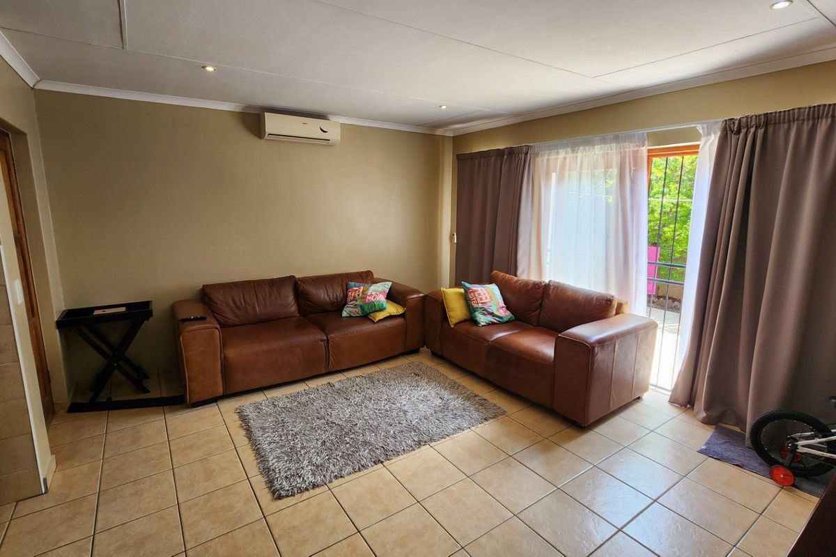 A comfortable living room featuring tiled flooring, a wall-mounted air conditioning unit, and direct access to the outdoor area through a sliding glass door.