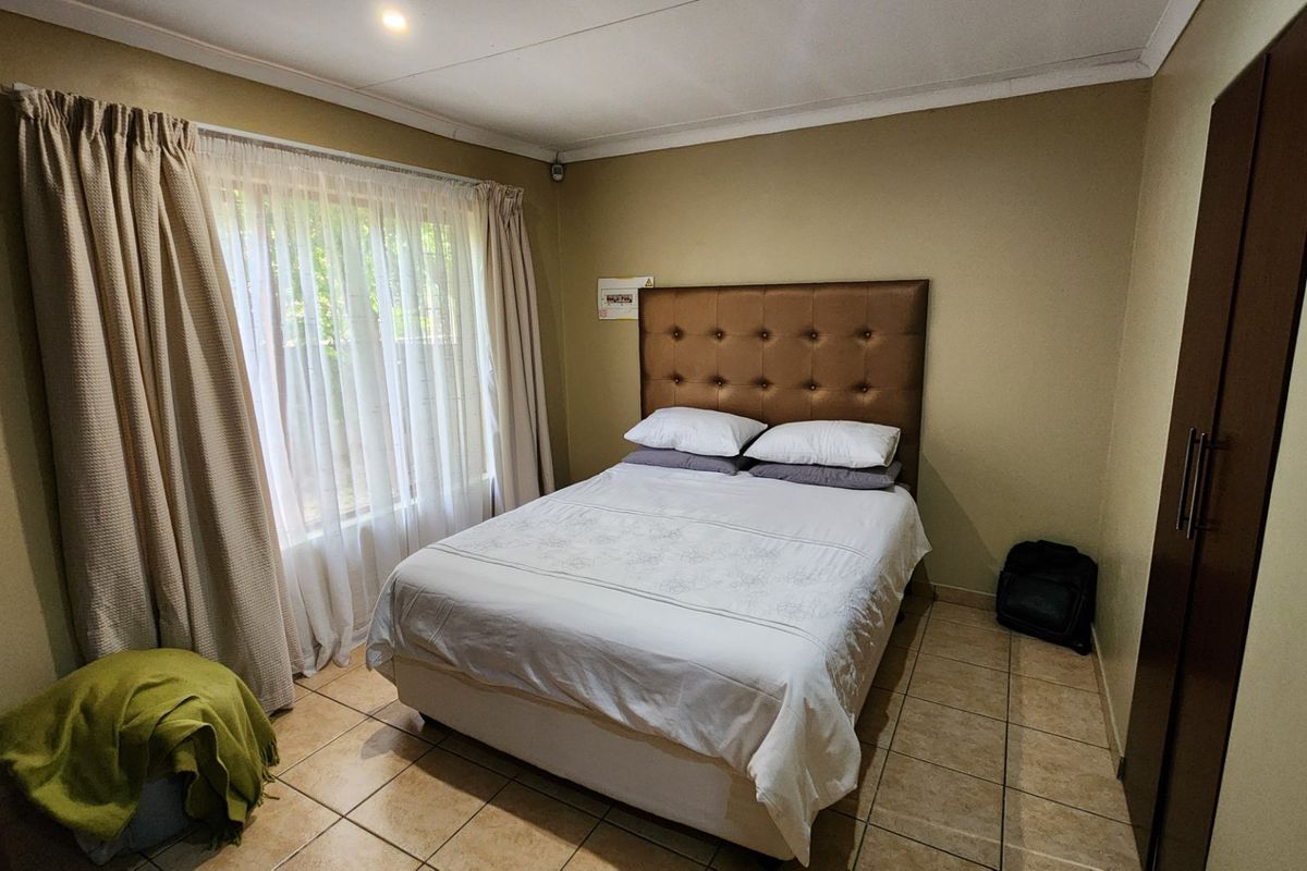 A functional bedroom featuring tiled flooring, a built-in wardrobe, and neutral wall tones, offering a comfortable and practical living space.
