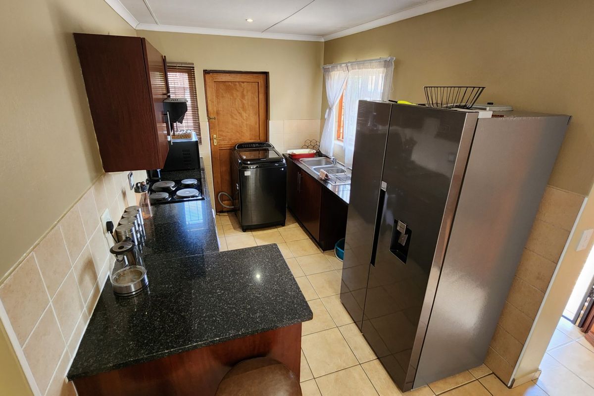A functional kitchen featuring dark wood cabinetry, granite countertops, a tiled backsplash, and a double sink with direct access to an exterior door.