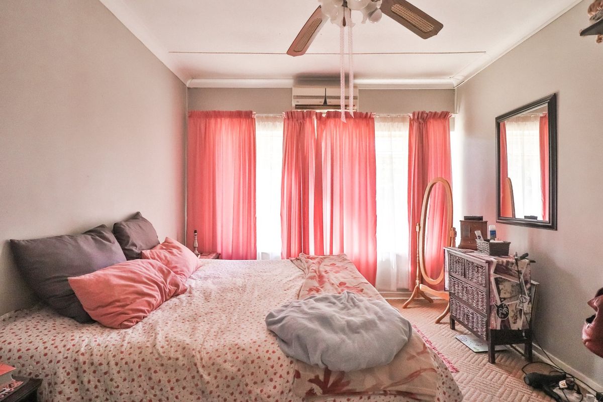 A bedroom featuring a ceiling fan and a wall-mounted air conditioning unit, providing climate control and ventilation.