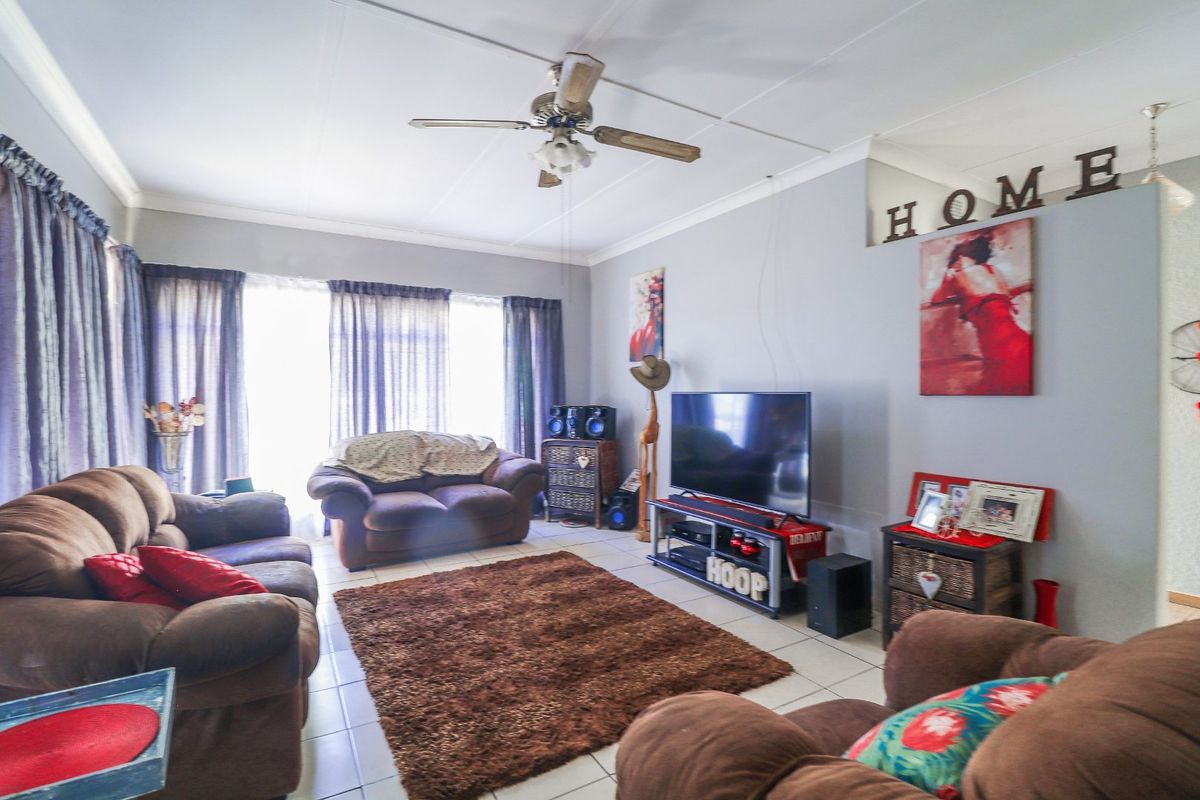 A comfortable living room featuring tiled flooring and a ceiling fan, providing a functional and inviting space for relaxation.