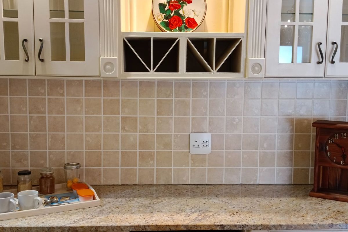 A kitchen workspace featuring granite countertops, tiled backsplash, and built-in cabinetry with integrated wine storage.