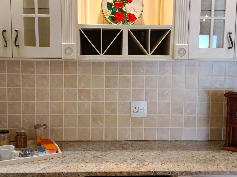 A kitchen workspace featuring granite countertops, tiled backsplash, and built-in cabinetry with integrated wine storage.