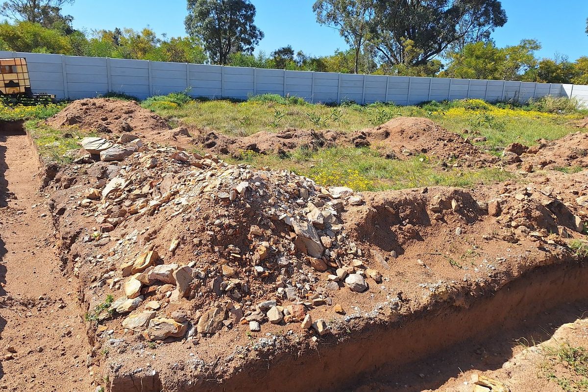 Vacant residential land featuring excavated foundation trenches and a perimeter precast concrete boundary wall.