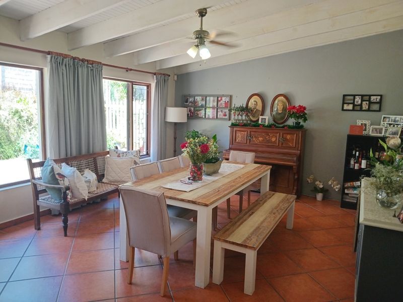 Spacious dining area featuring exposed timber ceiling beams, terracotta floor tiles, and large sliding glass doors providing natural light and garden access.