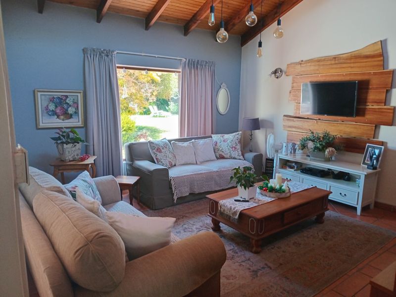 Cozy living room featuring exposed timber ceiling beams, terracotta flooring, and a rustic timber feature wall with integrated television mounting.
