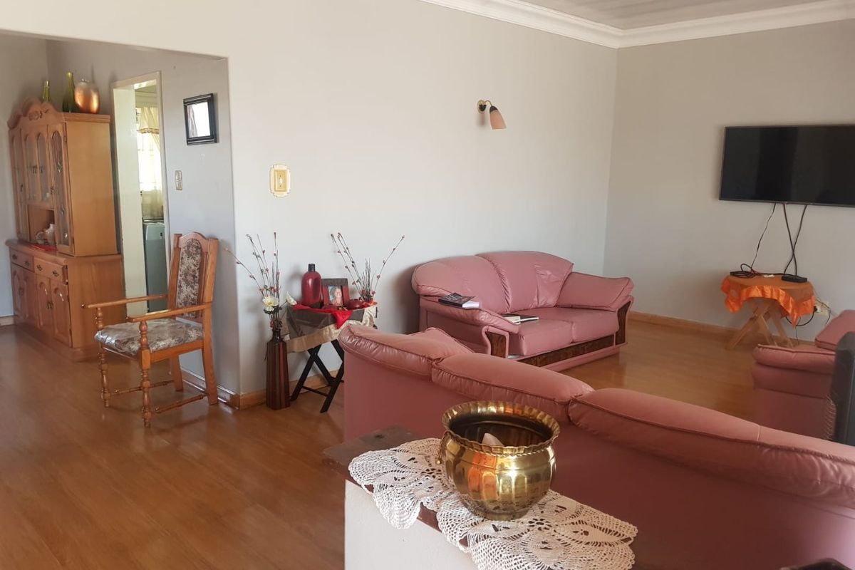 Spacious living room featuring laminate flooring and decorative cove cornicing, providing a neutral base for potential interior updates.