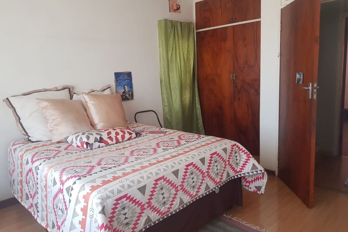 A functional bedroom featuring built-in wooden wardrobes and laminate flooring, offering a practical layout with standard finishes.