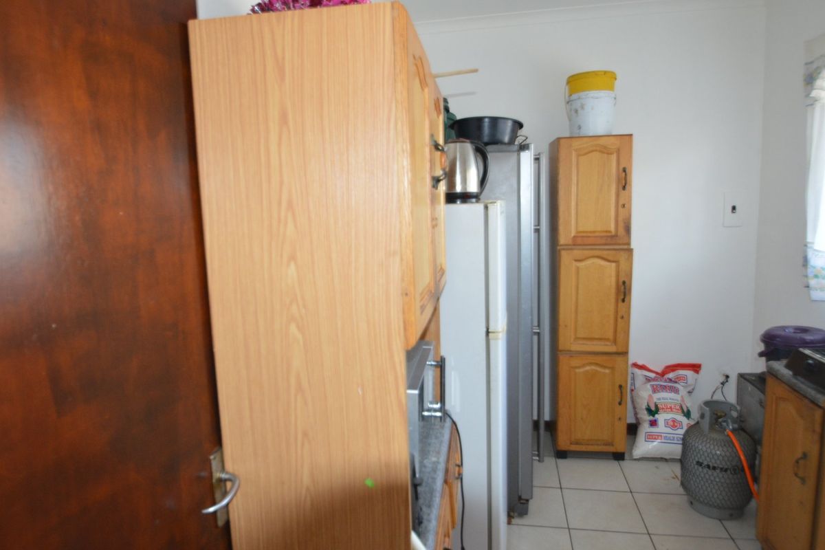 A compact kitchen featuring dated wooden cabinetry and tiled flooring, offering potential for a modern renovation to enhance functionality and aesthetic appeal.