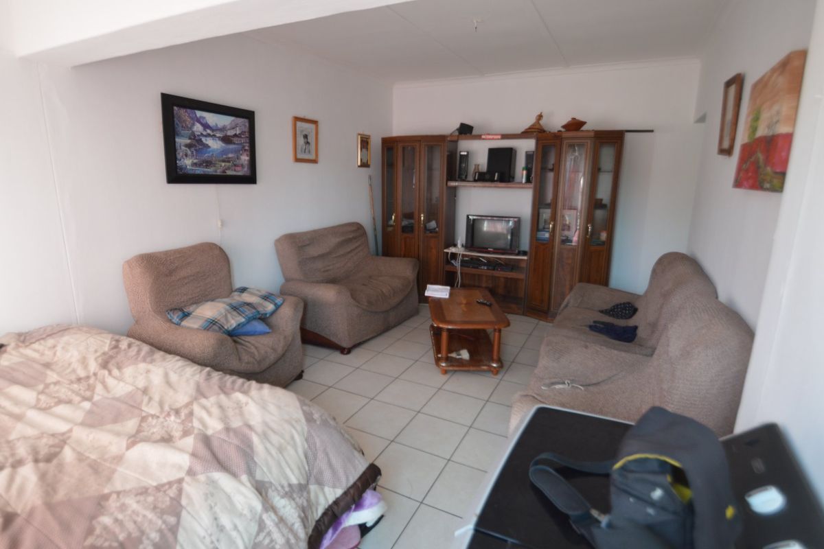 A living room area featuring tiled flooring and a neutral layout, offering a functional space ready for modernization and personal styling.