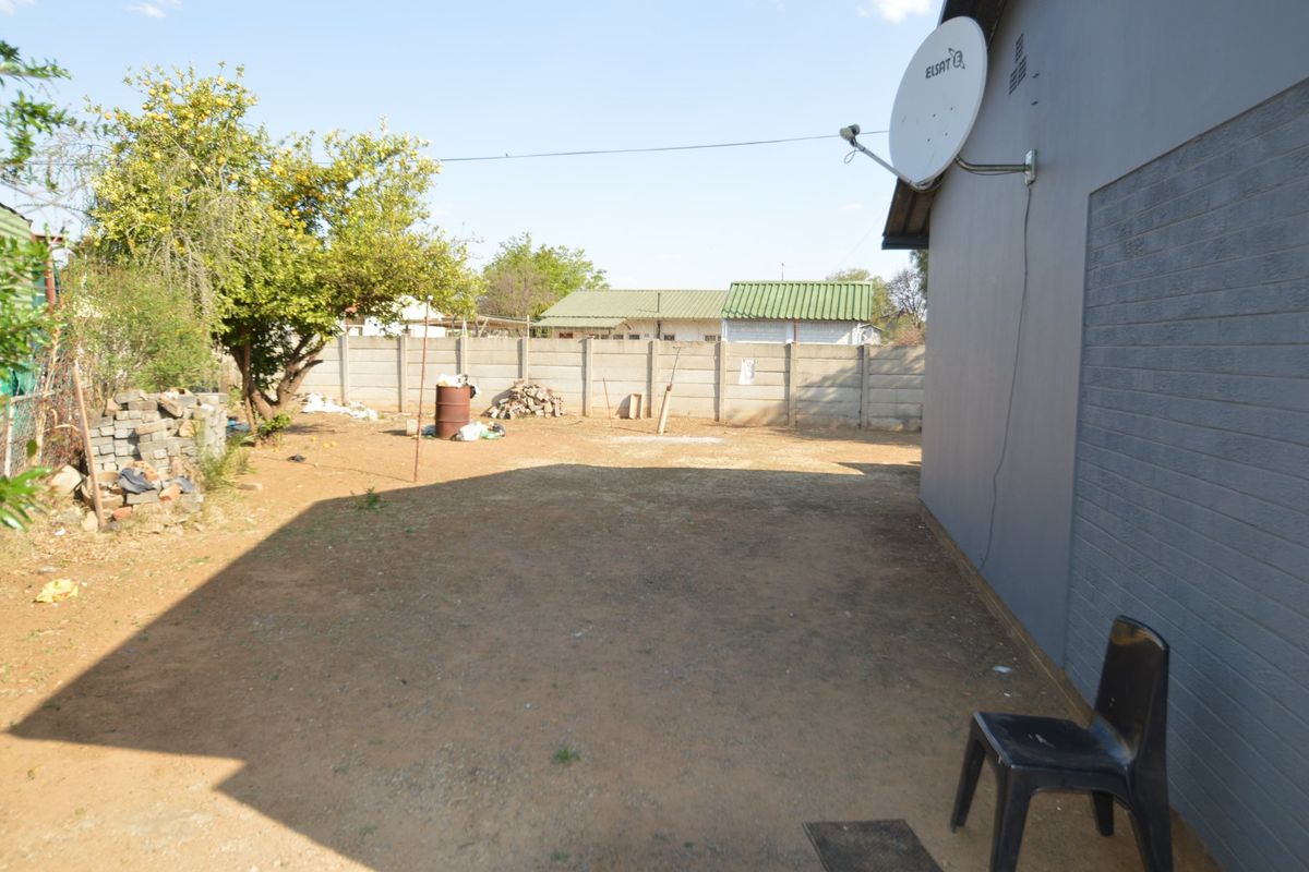 A rear yard area featuring a precast concrete boundary wall and a satellite dish mounted on the exterior wall of the property.