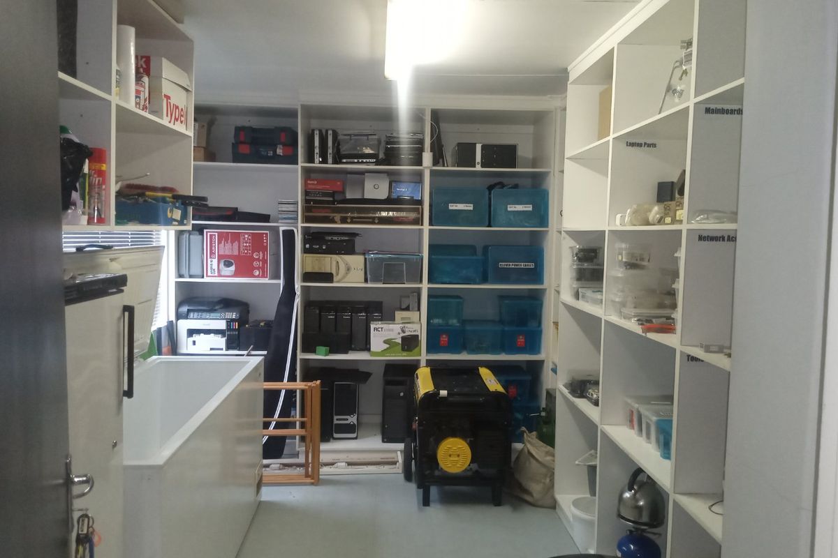 A functional utility or storage room featuring extensive built-in white shelving units, providing ample organized storage space for equipment and supplies.