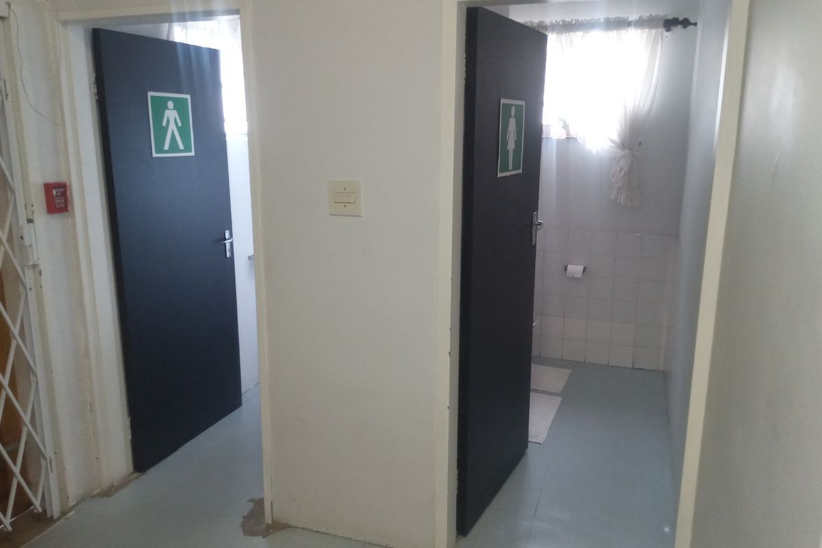 Commercial restroom facility featuring separate male and female entrances with basic tiled flooring and functional door hardware.