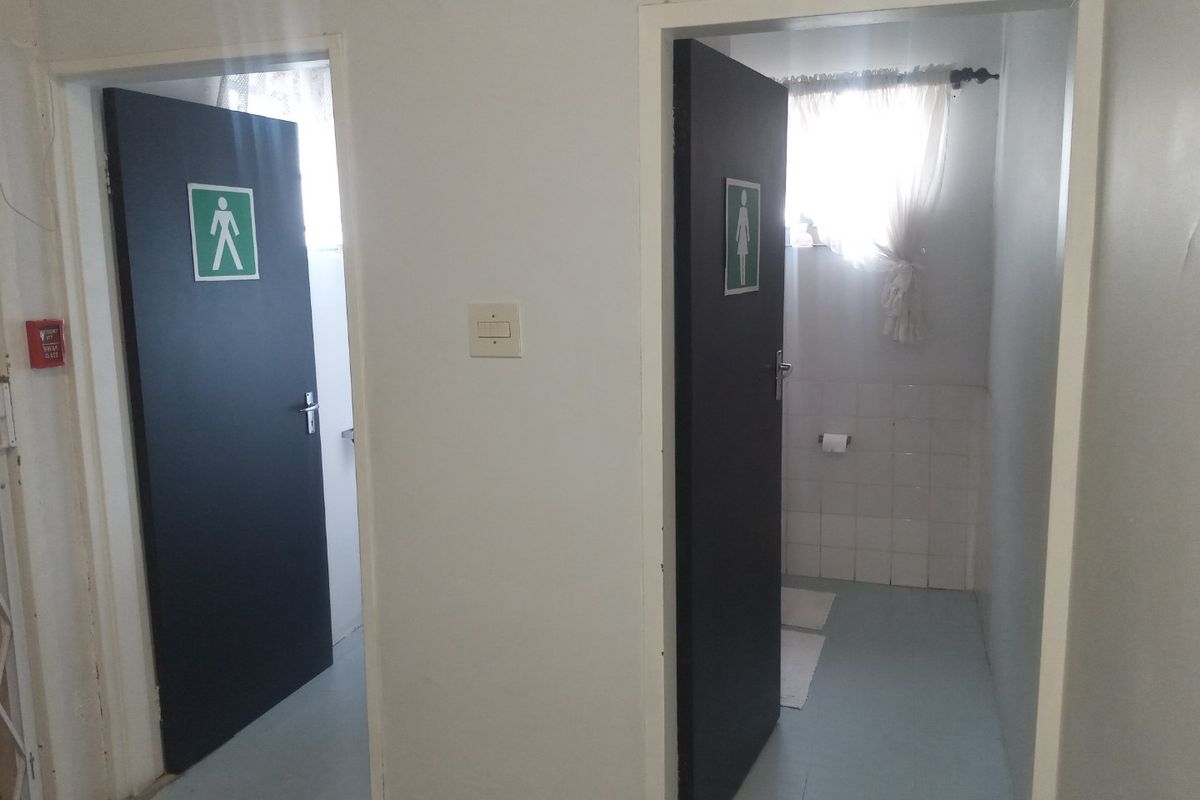 Commercial hallway featuring separate male and female restroom access points with clear signage and functional fire safety equipment.