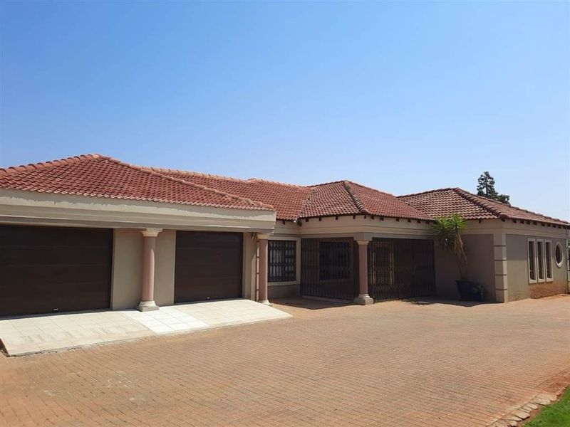 Front elevation of a single-story house featuring a double garage, tiled roof, and a spacious paved driveway.