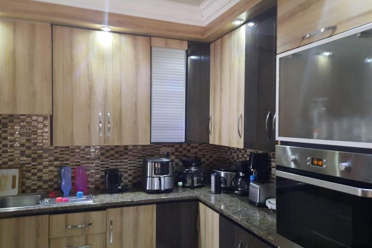 Modern kitchen featuring two-tone wood and dark cabinetry, granite countertops, mosaic tile backsplash, and integrated stainless steel oven.