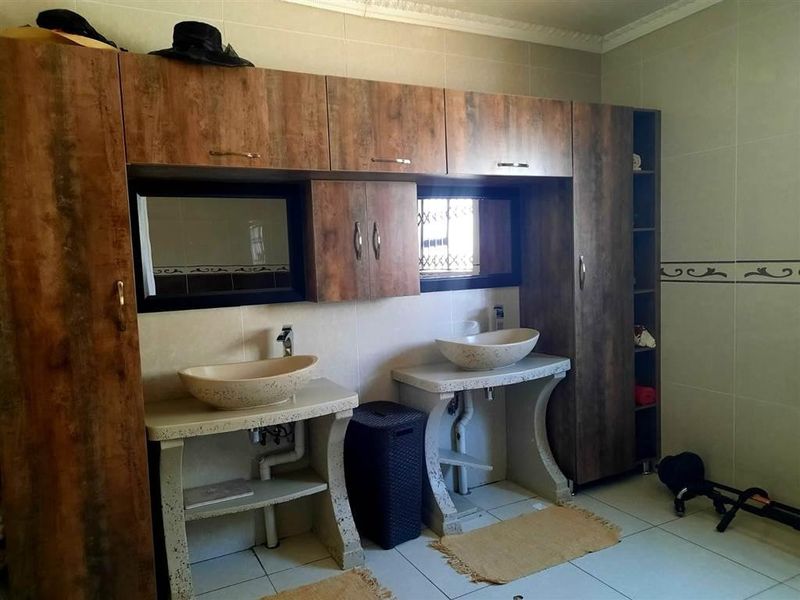 Bathroom featuring a double vanity with vessel sinks, built-in cabinetry, and tiled finishes.