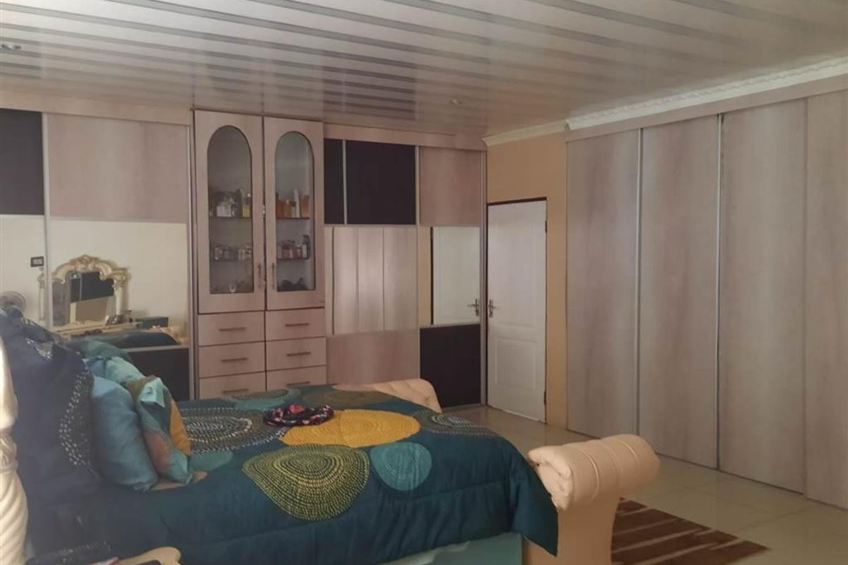 Spacious bedroom featuring extensive built-in cabinetry, tiled flooring, and a panelled ceiling.