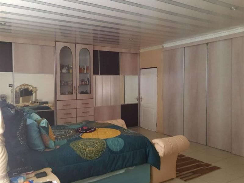 Spacious bedroom featuring extensive built-in cabinetry, tiled flooring, and a panelled ceiling.