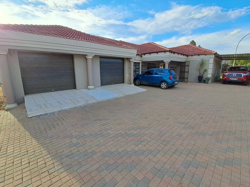 Front elevation of a residential property featuring a double garage, paved driveway, and tiled roof structure.