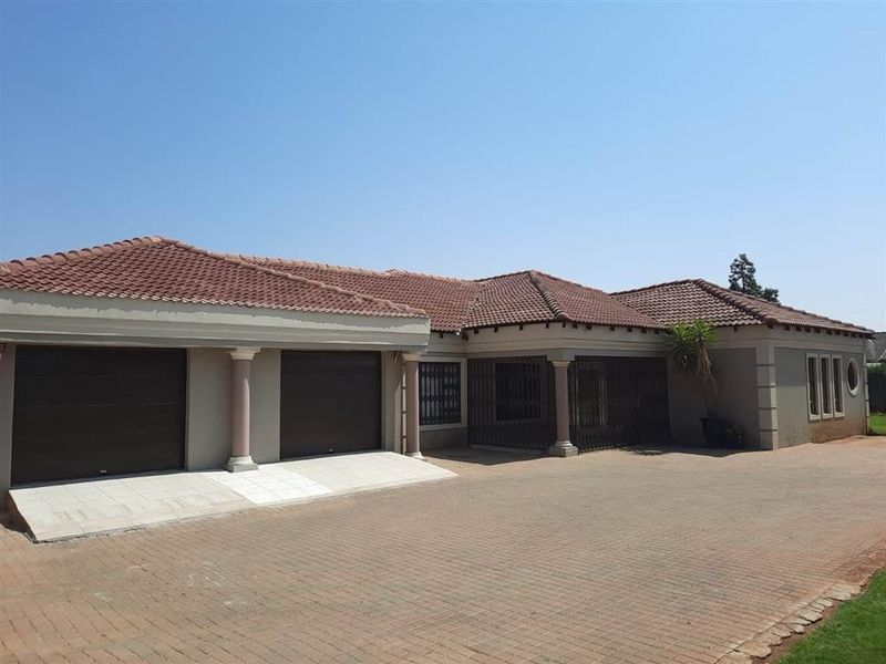 Front exterior view of a single-story house featuring a tiled roof, double garage, and a spacious paved driveway.