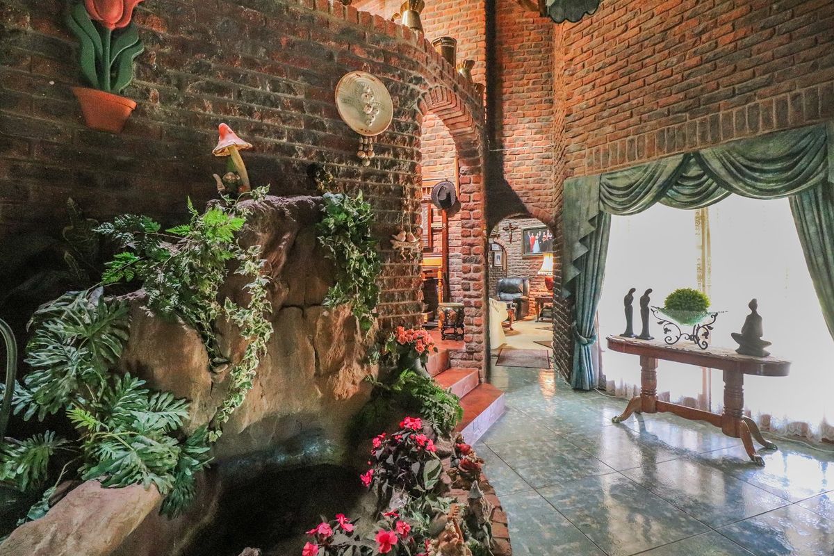 A unique living area featuring rustic exposed brick walls, an arched architectural transition, and a built-in indoor water feature with tiled flooring.