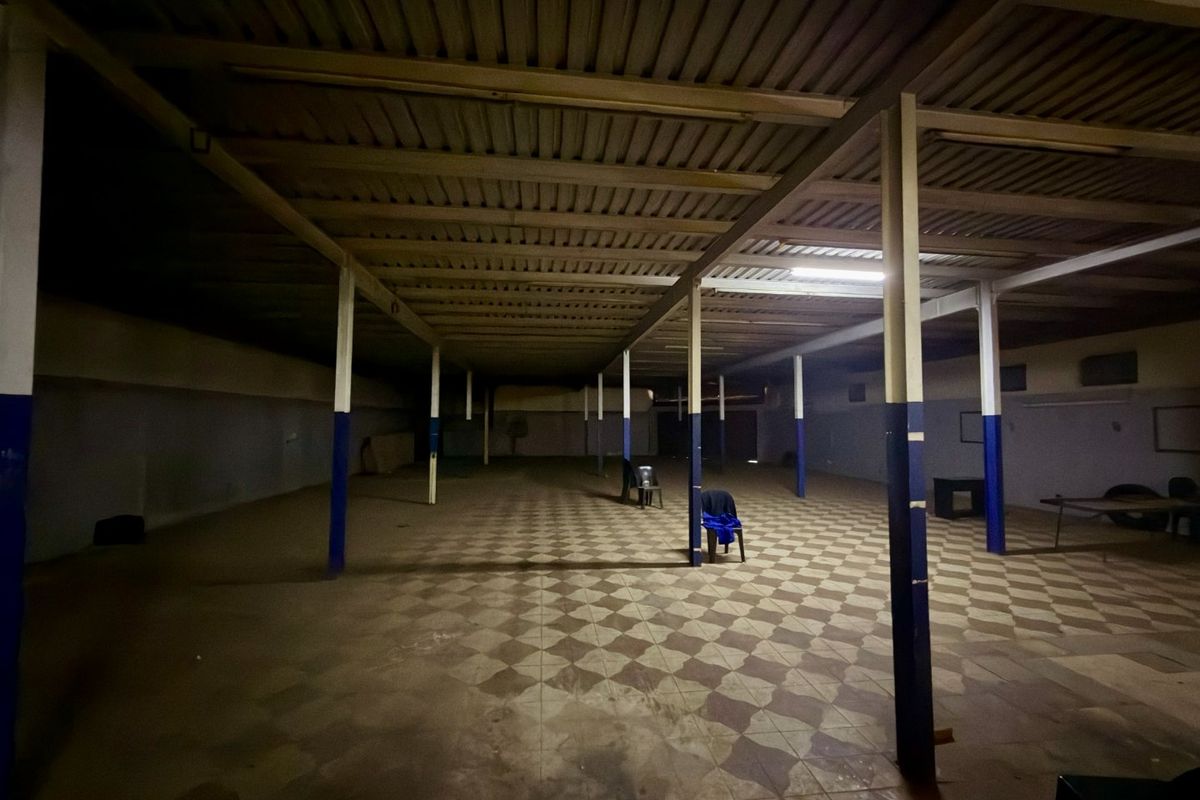 A large, open-plan commercial space featuring exposed steel roof beams, support columns, and tiled flooring, suitable for various business or storage applications.