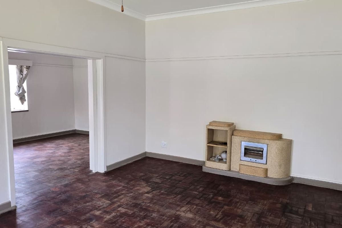An empty living room featuring original parquet flooring, a built-in fireplace, and classic architectural details like picture rails and cove cornicing.
