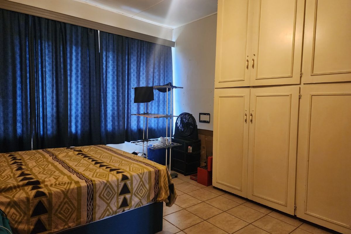 A bedroom featuring built-in cupboards and tiled flooring, offering a functional space with potential for modernization.