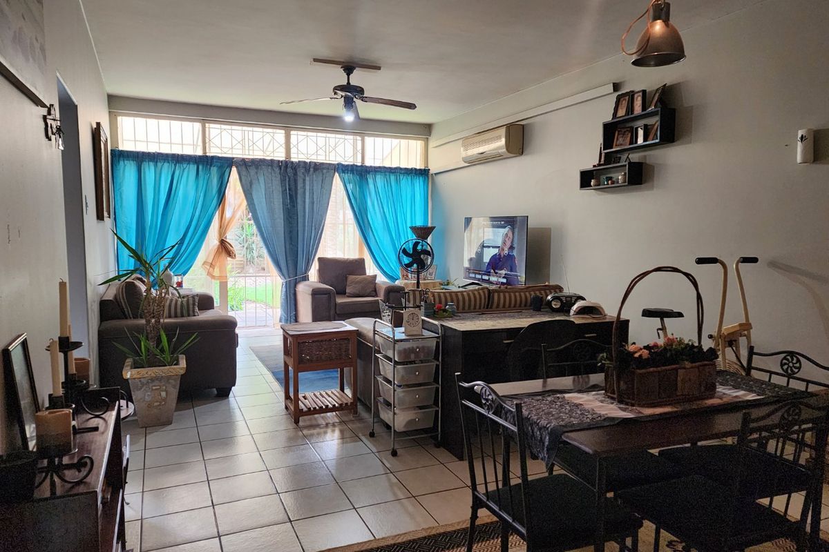 Open-plan living and dining area featuring tiled flooring, a ceiling fan, split-system air conditioning, and large glass doors leading to the exterior.