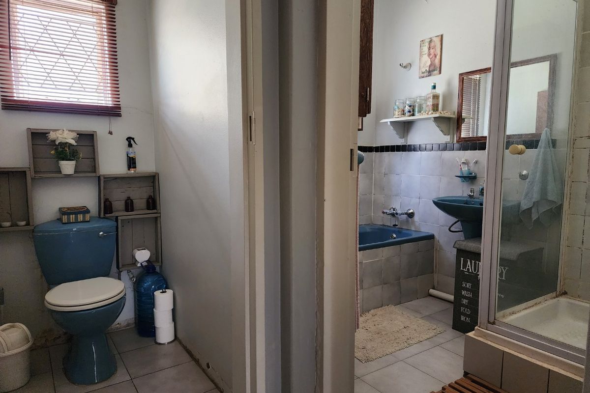 A dated bathroom featuring blue sanitary ware, a separate shower enclosure, bathtub, and pedestal sink with tiled finishes throughout.