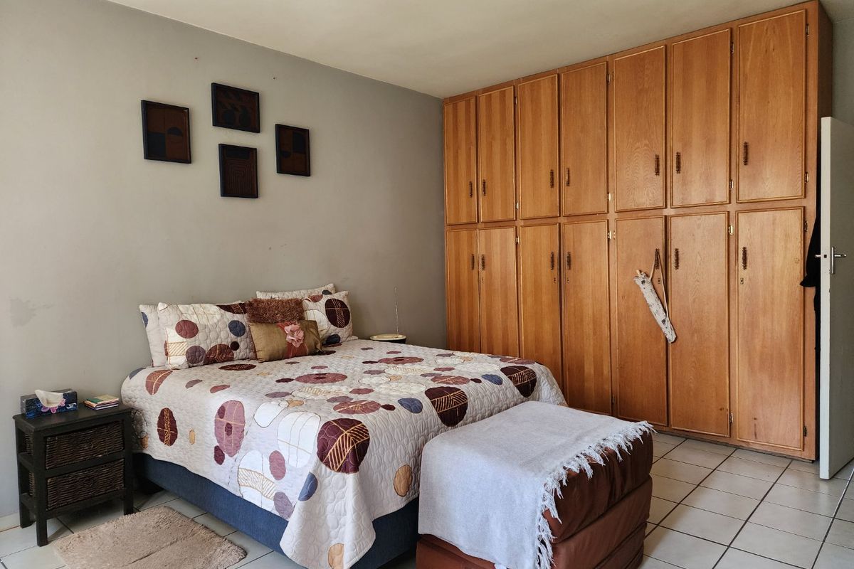 A bedroom featuring extensive floor-to-ceiling built-in wooden cabinetry and tiled flooring, offering ample storage space.