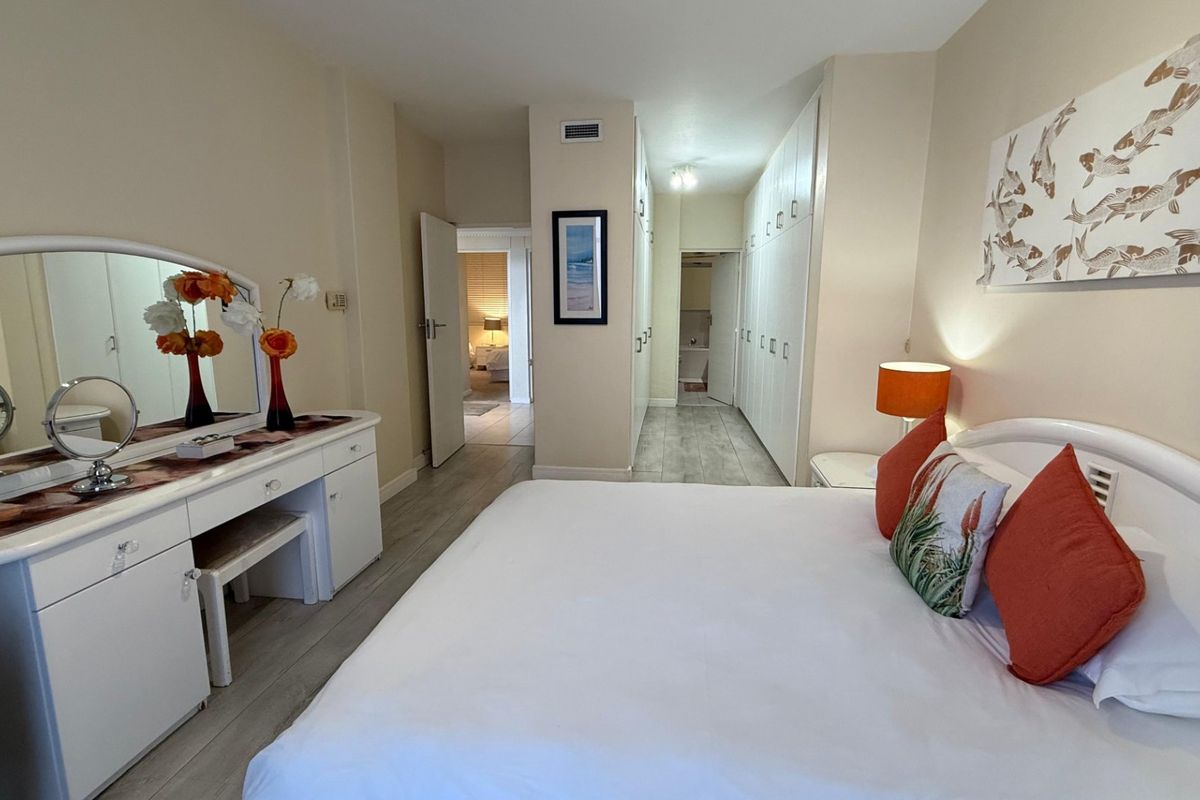 Spacious bedroom featuring extensive built-in cabinetry, neutral tiled flooring, and direct access to an en-suite bathroom area.